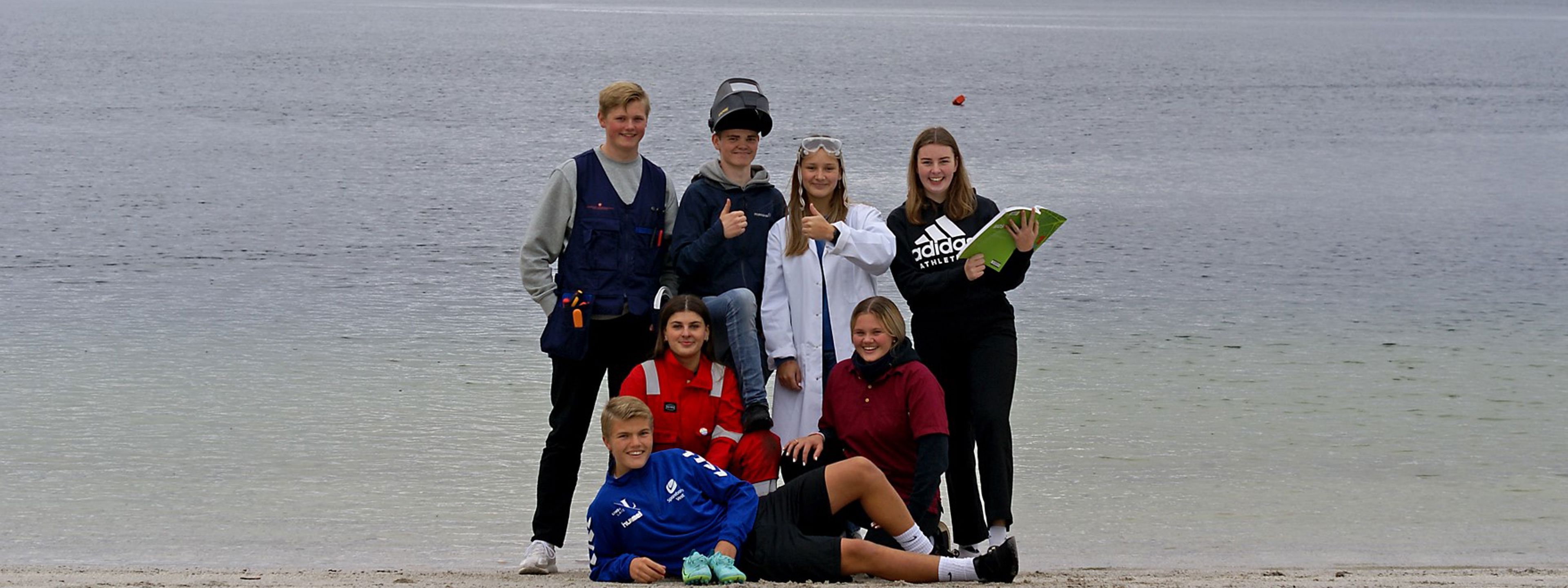 Elevar på stranda. kledd i klede knytt til studieretningane sine.